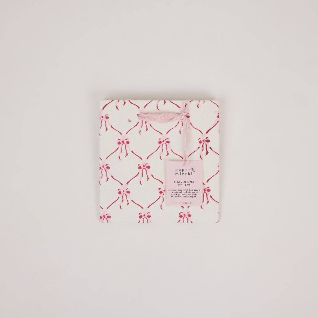 Packaged product with pink bow pattern on a light gray background