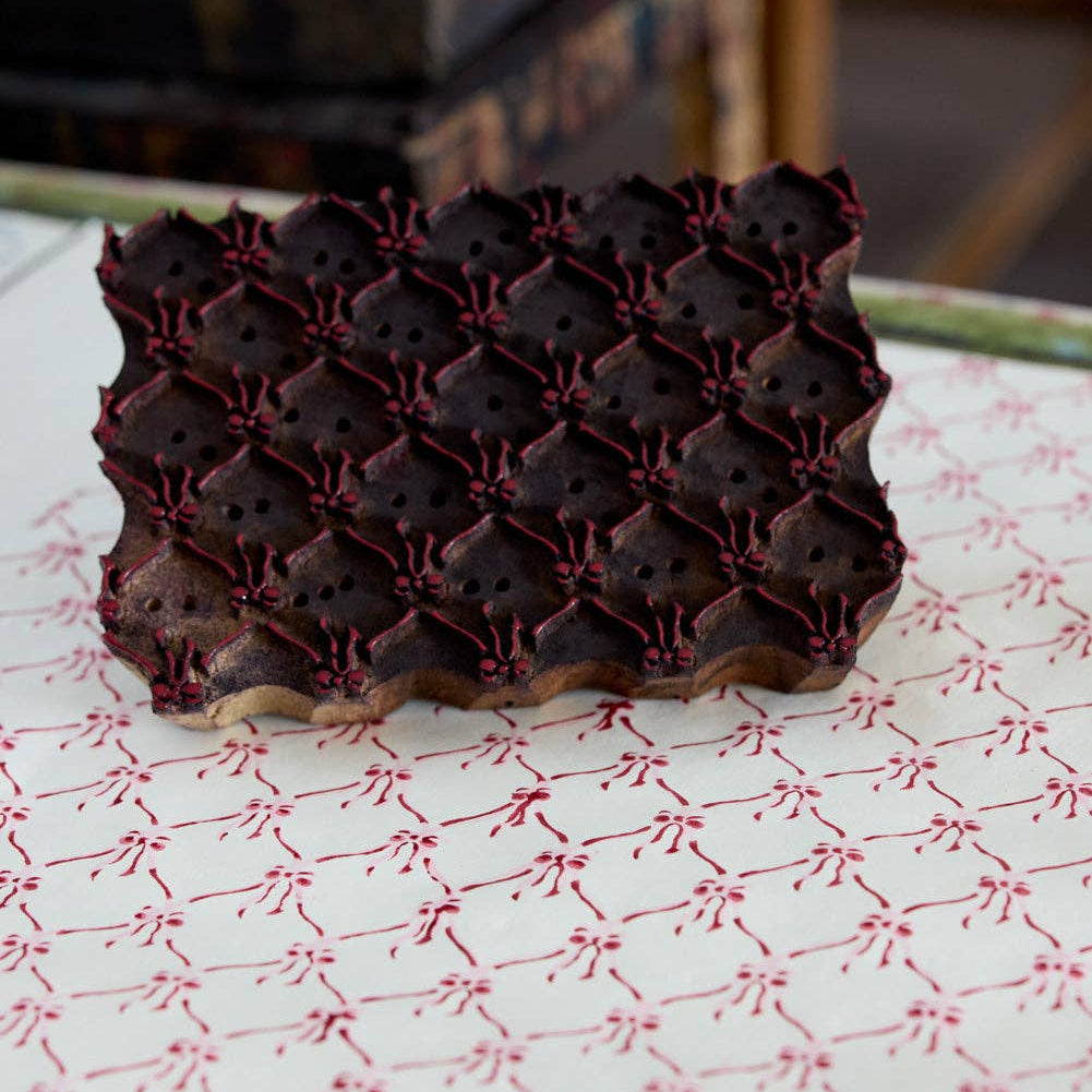 Dark chocolate truffles with a red pattern on a white and red patterned surface.