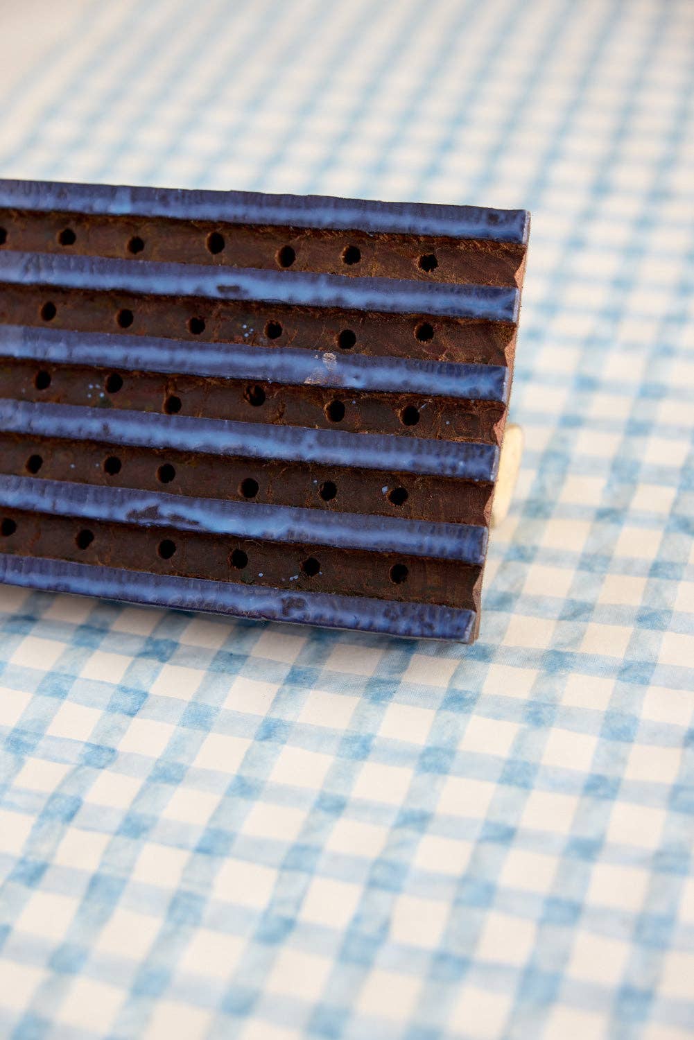 Rectangular chocolate bar with a textured surface on a blue and white checkered fabric background