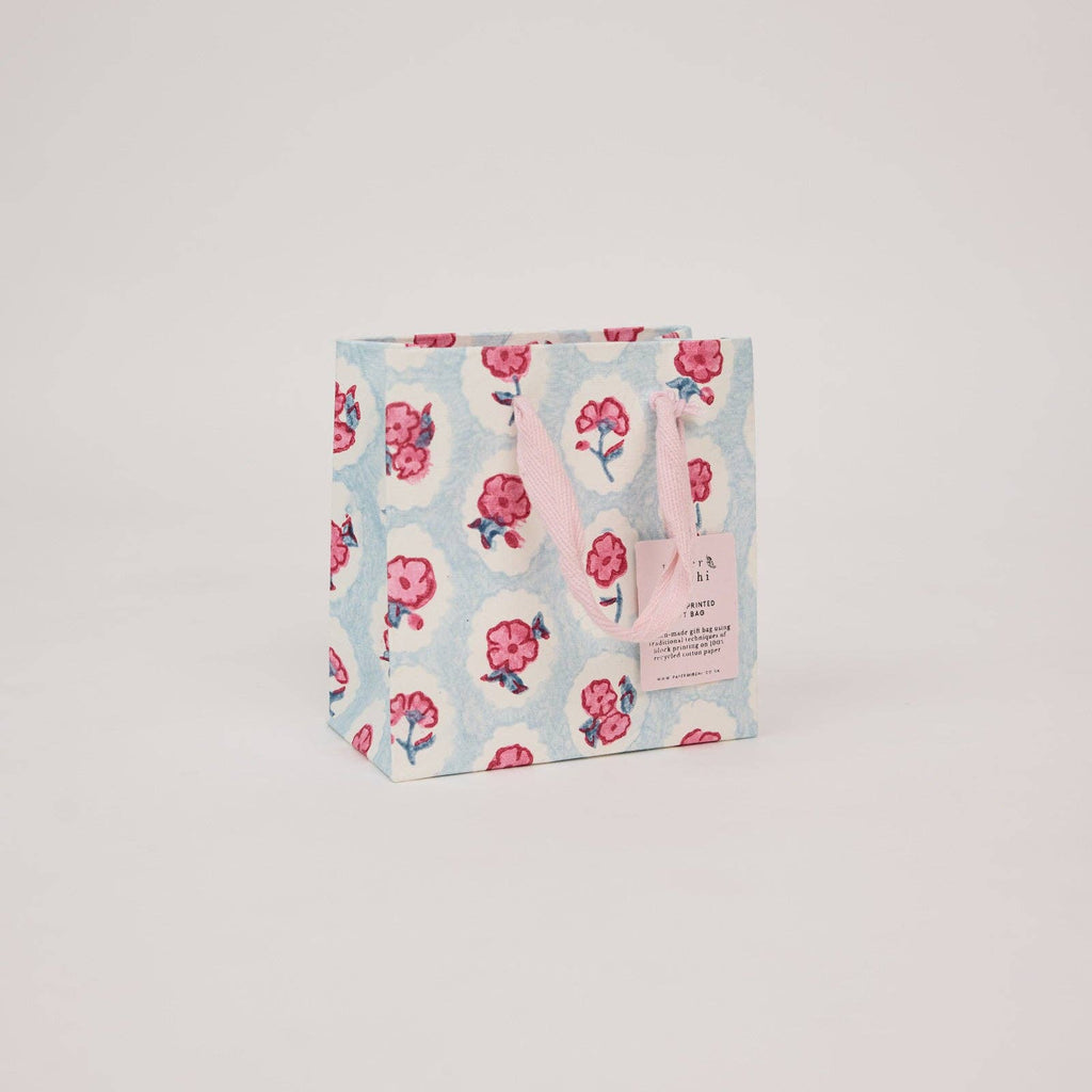 Floral-patterned bag with pink handles on a light gray background