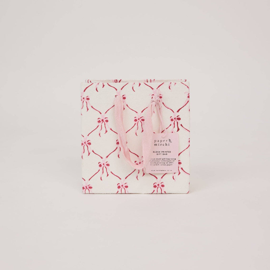 Pink gift bag with bow pattern on a light gray background