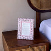 Decorative sign on a wooden nightstand with a wicker headboard in the background
