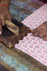 Person working with fabric and a wooden tool on a colorful surface