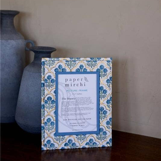 Decorative picture frame with intricate blue and white design on a wooden surface.