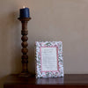 Wooden candlestick with a blue candle next to a decorative box on a wooden surface.