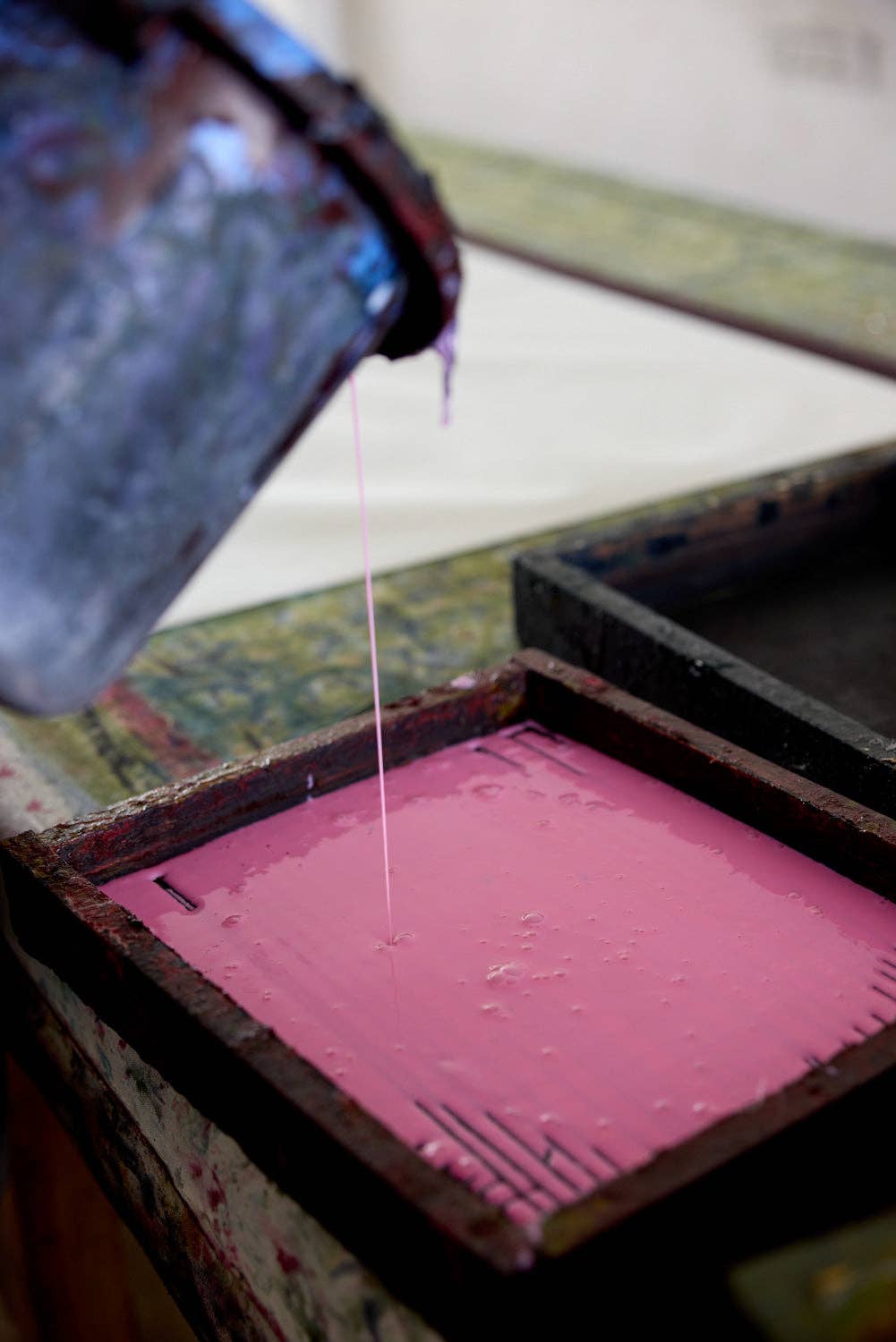 Pink ink being poured into a printing tray with a blurred background