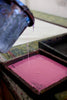 Pink ink being poured into a printing tray with a blurred background