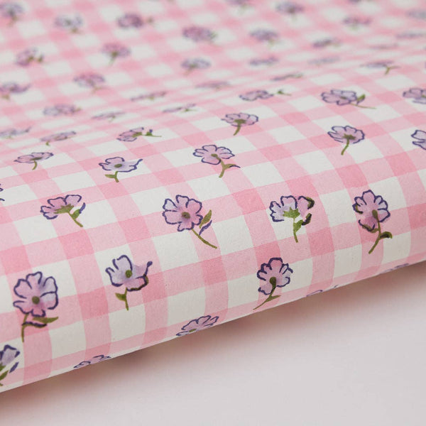 Pink checkered fabric with small floral patterns on a light pink background