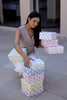 Woman arranging patterned gift boxes on a tiled floor