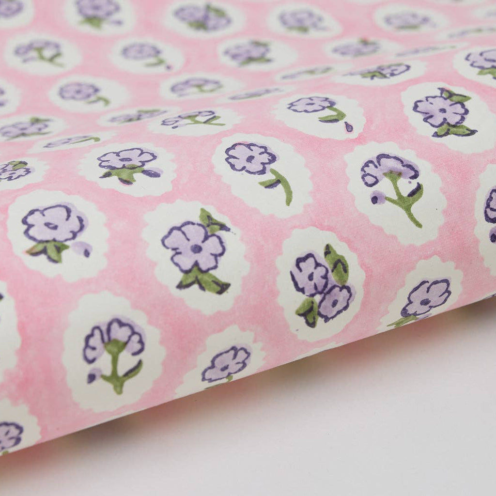 Pink fabric with purple floral patterns on a white background