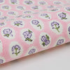 Pink fabric with purple floral patterns on a white background