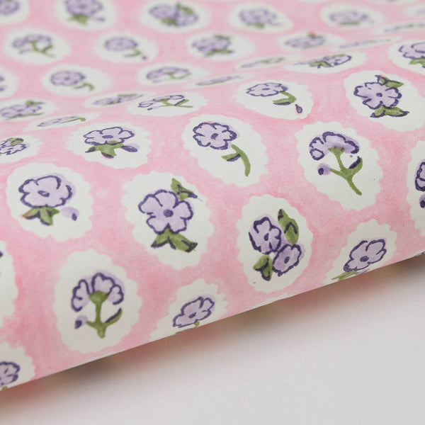 Pink fabric with purple floral patterns on a white background