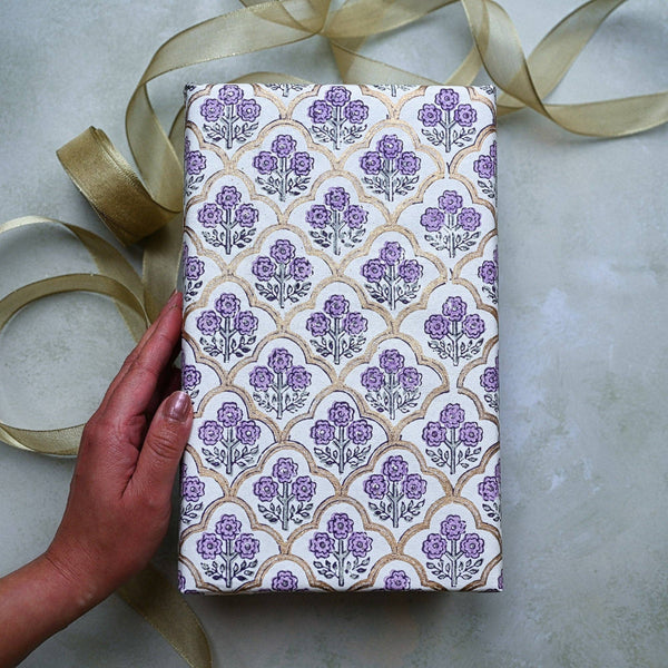 Gift box with floral pattern and gold ribbon on a light surface