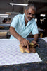 Man working with fabric and a wooden tool in a workshop setting