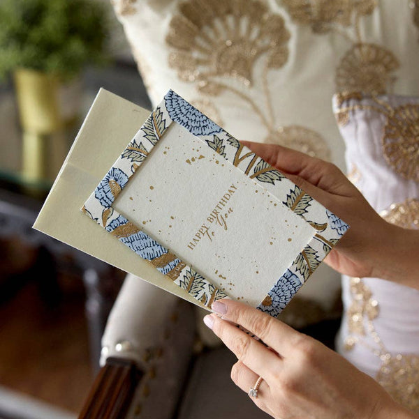 Person holding a decorative card with intricate patterns and text.