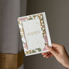 Hand holding a floral birthday card against a neutral background