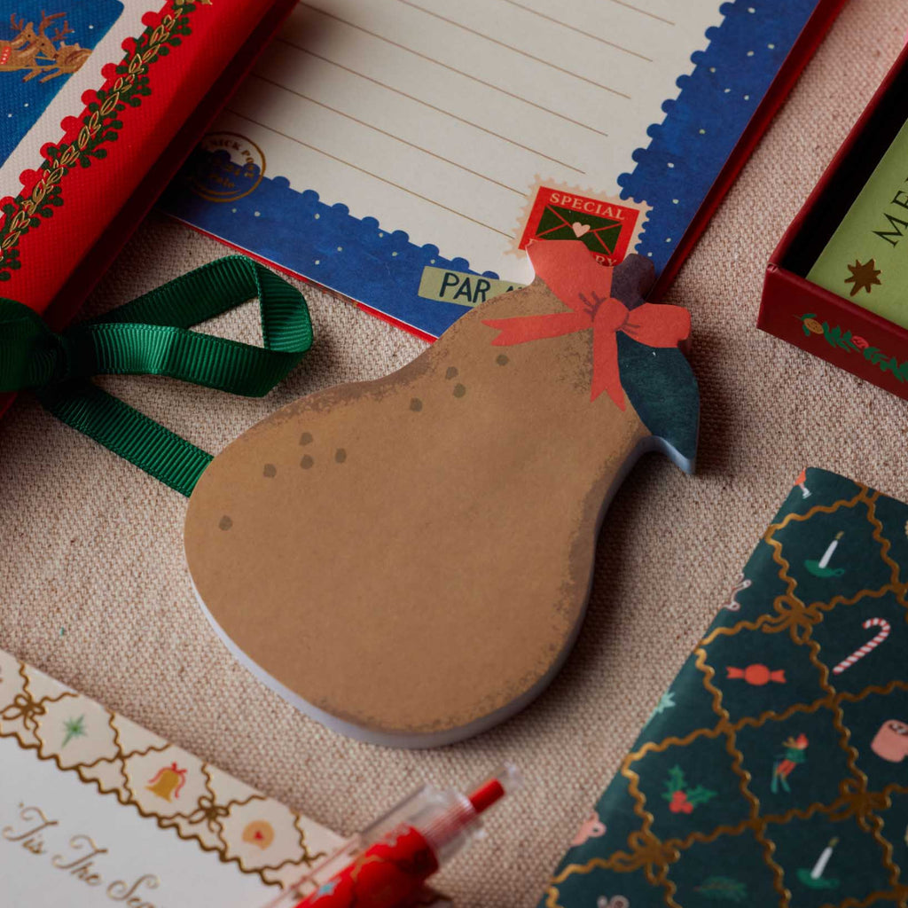 Cardboard pear-shaped gift tag with decorative elements on a textured surface.
