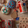 Collection of Christmas-themed items including a mug, cards, and decorative elements on a textured surface.