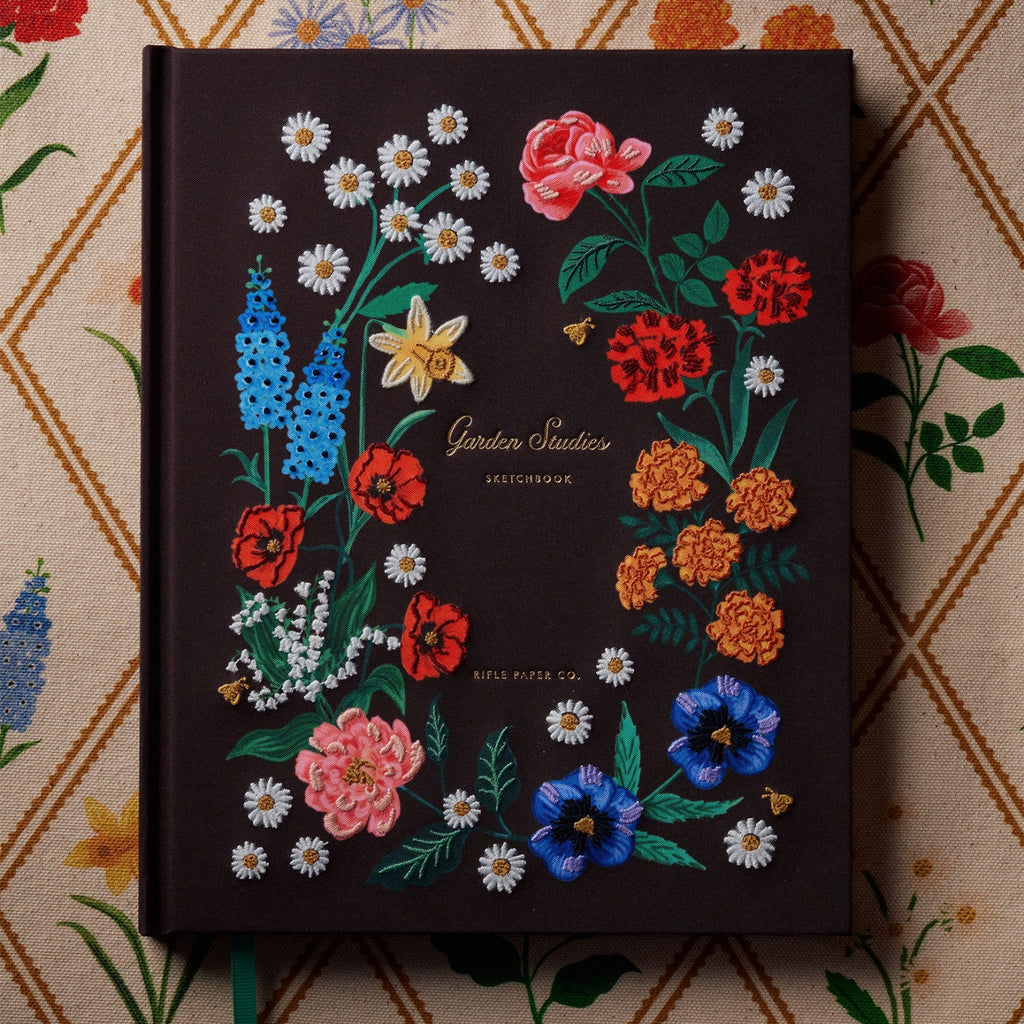 Decorative notebook with embroidered floral designs on a patterned background