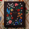 Decorative notebook with embroidered floral designs on a patterned background