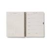 Spiral-bound planner with a grid layout on a white background