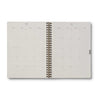 Open spiral-bound planner with grid and dot matrix pages on a white background