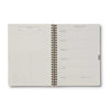 Open spiral-bound planner with daily schedule on a white background