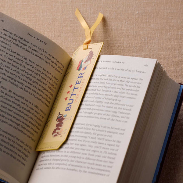 Open book with a decorative bookmark featuring the word 'BUTTER' on a textured surface.