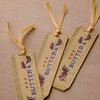 Three decorative butter labels with ribbons on a textured beige background