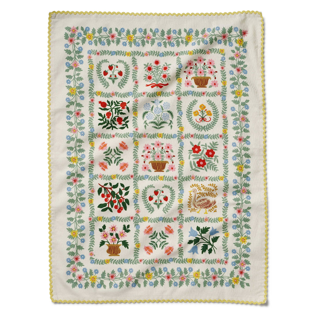 Embroidered quilt with floral and botanical patterns on a white background