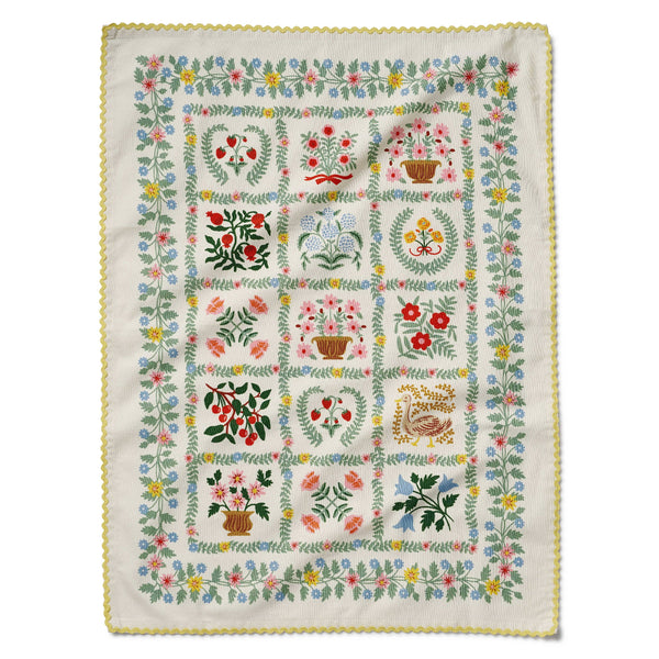 Embroidered quilt with floral and botanical patterns on a white background