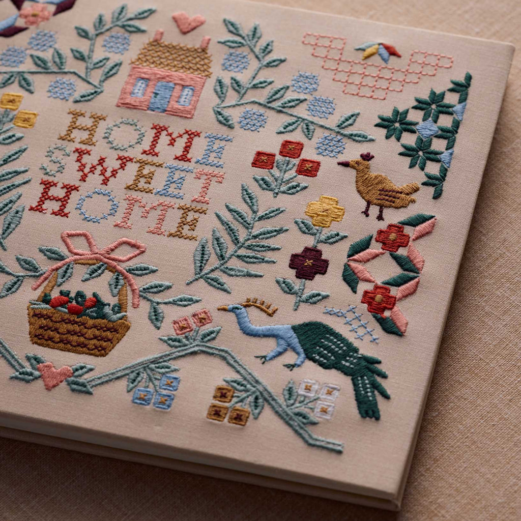 Embroidery with 'Home Sweet Home' text and various decorative elements on a beige background