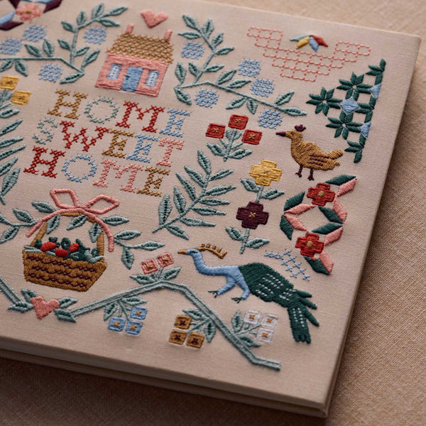 Embroidery with 'Home Sweet Home' text and various decorative elements on a beige background