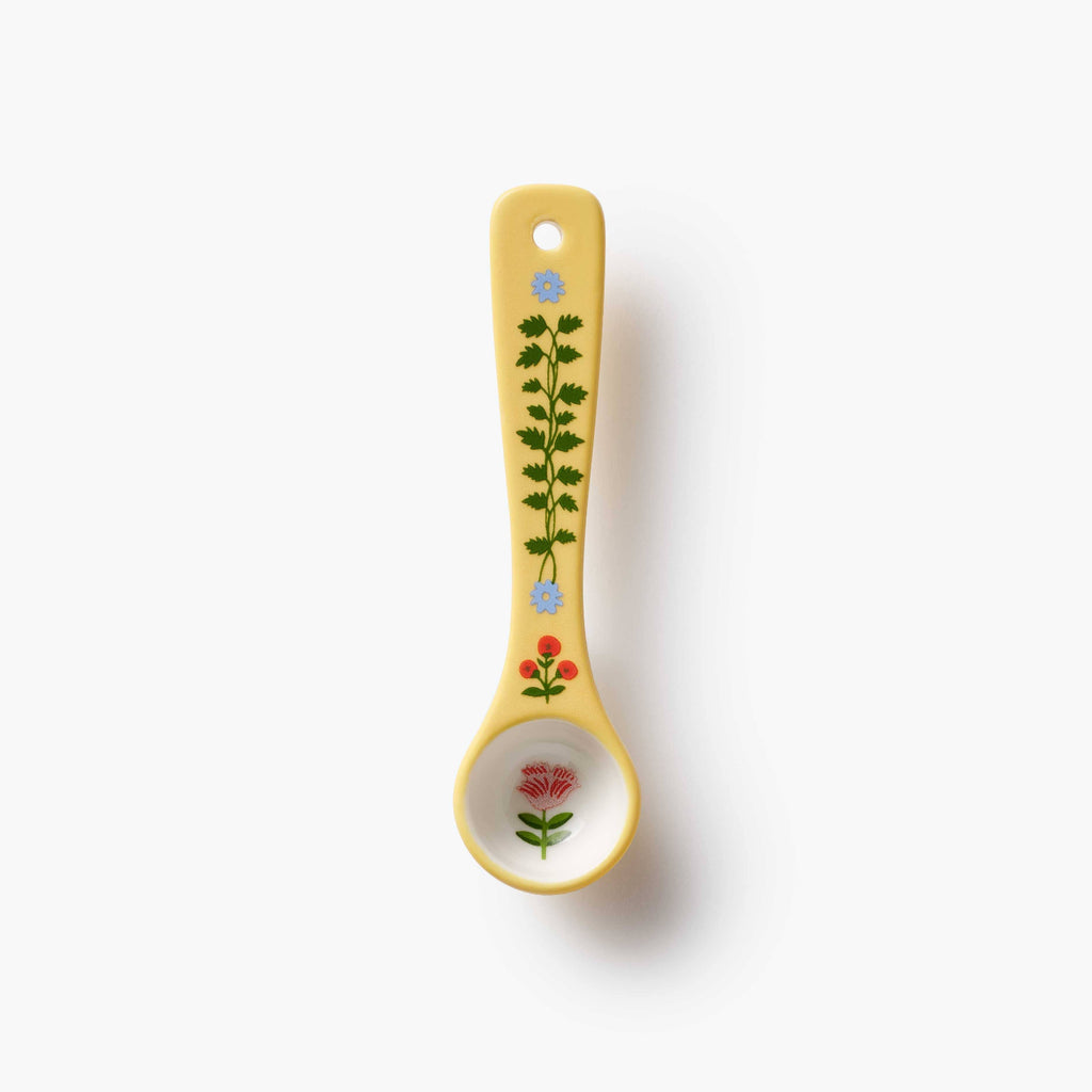 Decorative yellow spoon with floral patterns on a white background