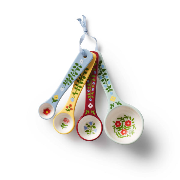 Set of four colorful measuring spoons with floral designs on a white background