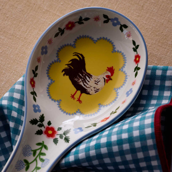 Decorative spoon rest with a rooster design on a checkered cloth