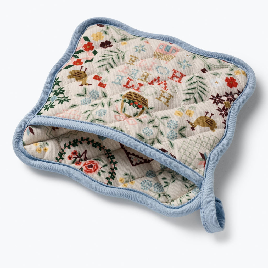Quilted pot holder with floral and nature-themed design on a white background