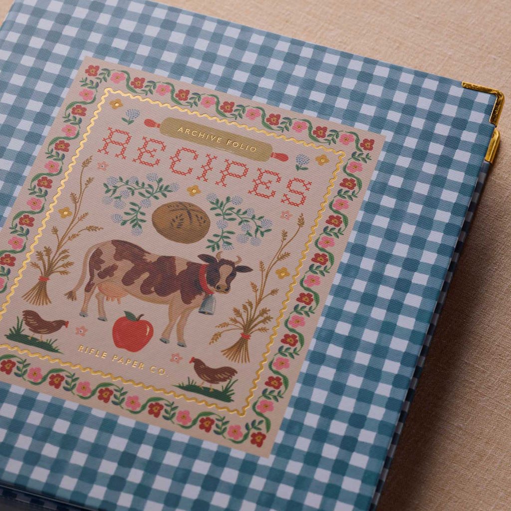 Cookbook with a checkered cover featuring a cow illustration and 'Recipes' text.