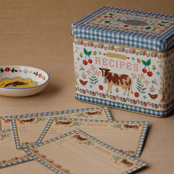 Decorative recipe tin with matching cards on a brown fabric background