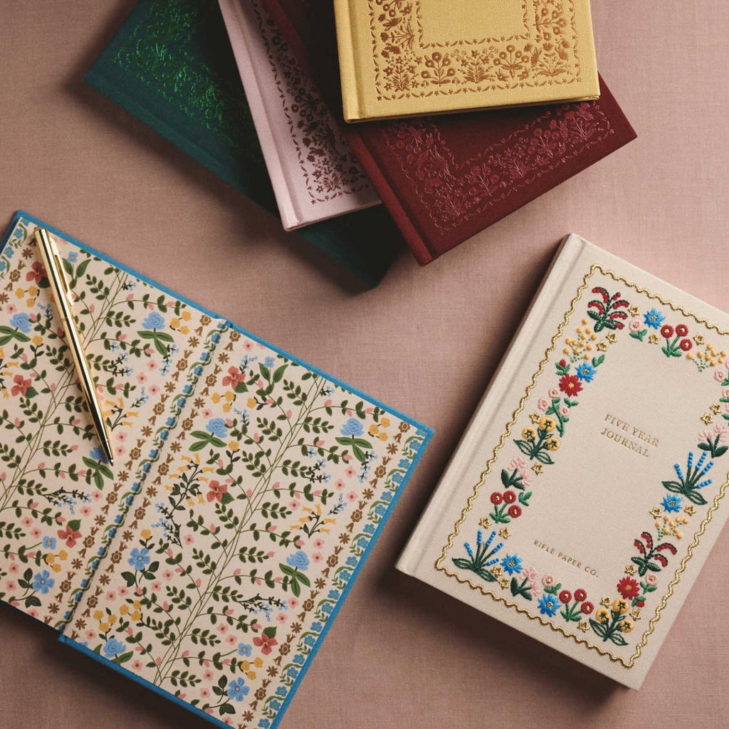 Decorative notebooks with floral patterns on a brown surface