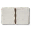 Open spiral-bound planner with floral design on a white background