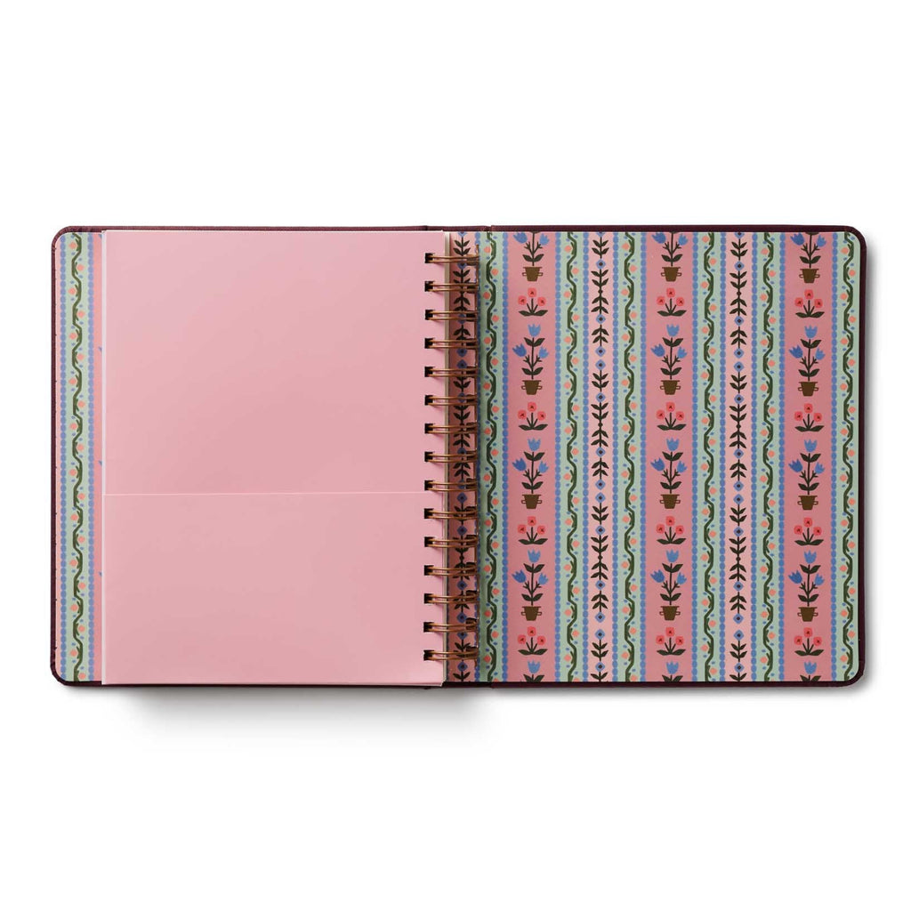Notebook with pink cover and patterned spine on a white background