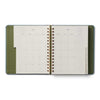 Open planner with green cover and white interior on a white background