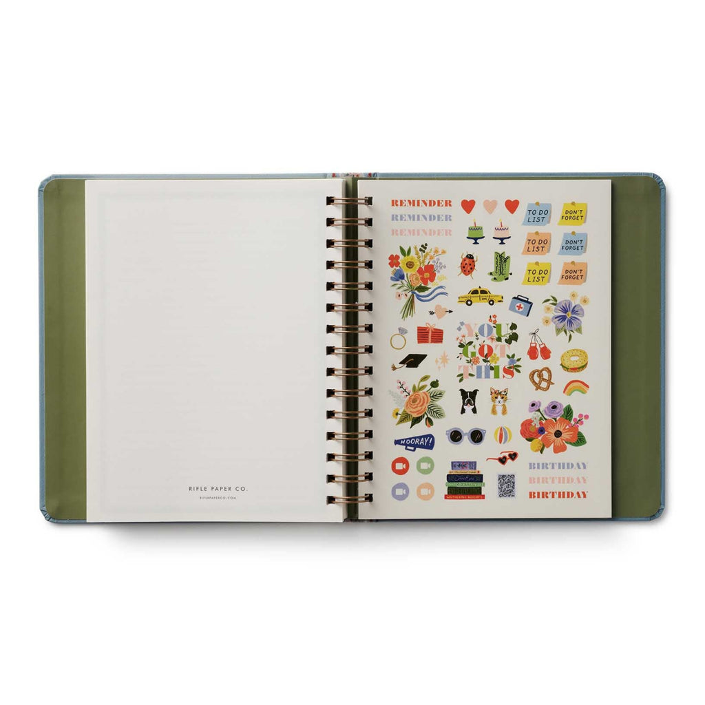 Open spiral-bound planner with decorative stickers on a white background