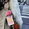 Keychain with charms attached to a green bag on a city street