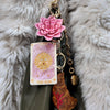 Keychain with tarot card, pink flower, and other charms on a fluffy gray background