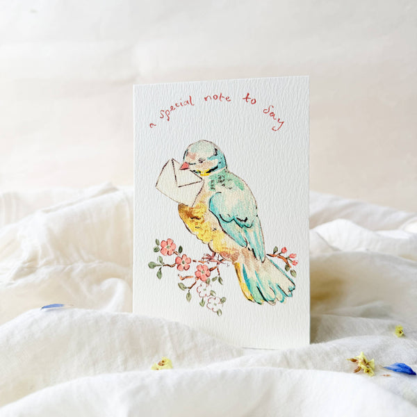 Card with a colorful bird illustration on a white surface