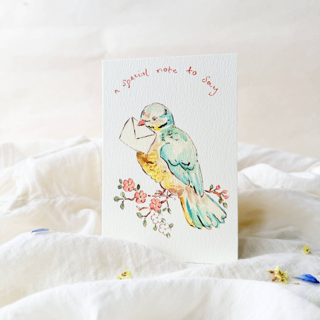 Card with a colorful bird illustration on a white surface