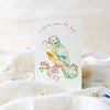Card with a colorful bird illustration on a white surface