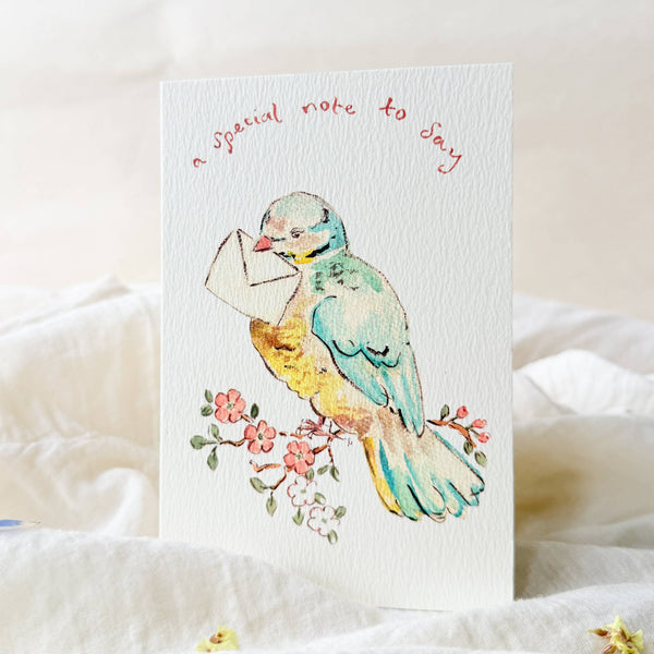 Greeting card with a colorful bird holding an envelope on a white background